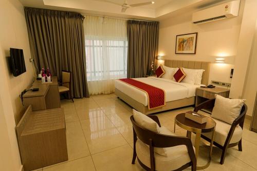AttingalにあるSooryaのベッド、テーブル、椅子が備わるホテルルームです。