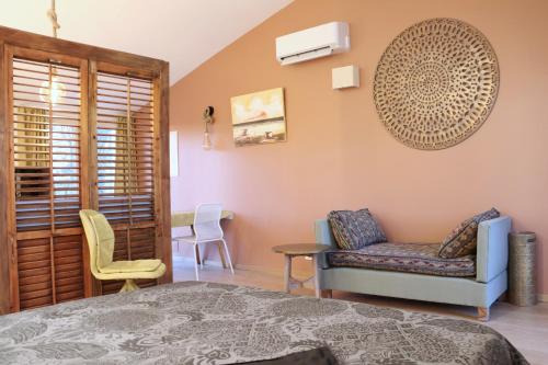 une chambre avec un lit, un canapé et une chaise dans l'établissement Le Jardin d'Érables St Remy 7 HA Piscine/Clim, à Paluds de Noves