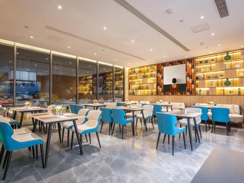 a dining room with tables and blue chairs at 银座佳悦精选（菏泽郓城水浒城店） in Yuncheng