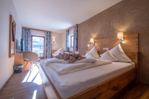 a bedroom with a large white bed in a room at Pension Garni Hochmoos in Lermoos