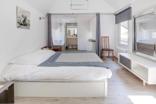a white bedroom with a bed and a window at Le Martray - Appartement coeur historique de Paimpol in Paimpol