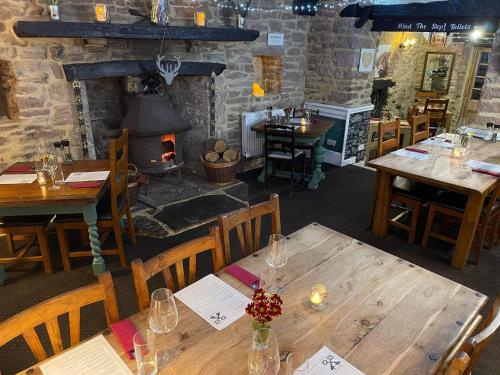 une salle à manger avec des tables en bois et une cheminée dans l'établissement Crosskeys Inn Guest Rooms in Wye Valley, à Hereford