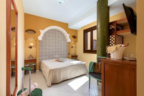 a bedroom with a bed in a room with a table at Hotel Sicilya in San Vito lo Capo