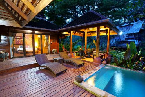 a wooden deck with a swimming pool and a house at Sukantara Cascade Resort and Spa in Mae Rim