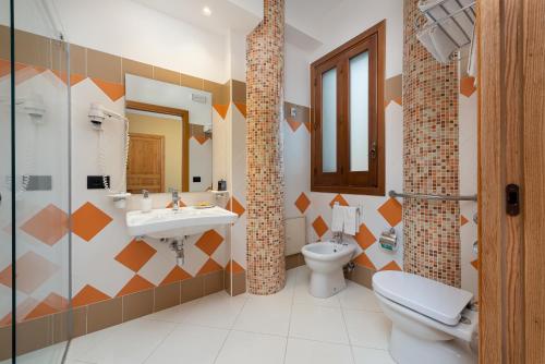 a bathroom with a sink and a toilet and a mirror at Hotel Sicilya in San Vito lo Capo