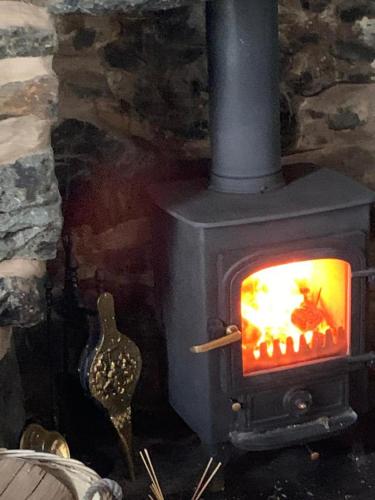 a black wood stove with a fire in it at Beautiful Cottage near Harlech with ocean views in Llanfair