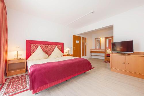 a bedroom with a large bed and a flat screen tv at Hotel Garni Lichtquelle in Bad Füssing
