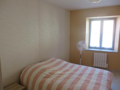 ein Schlafzimmer mit einem gestreiften Bett und einem Fenster in der Unterkunft Appartement 4 couchages in Clairvaux-les-Lacs