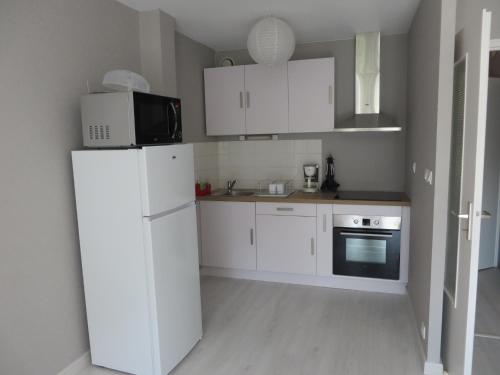 une cuisine blanche avec un réfrigérateur et un micro-ondes dans l'établissement Appartement 4 couchages, à Clairvaux-les-Lacs