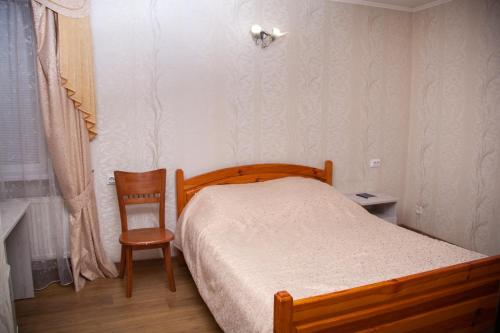 sypialnia z drewnianym łóżkiem i krzesłem w obiekcie Piligrim 2 w mieście Mikołajów