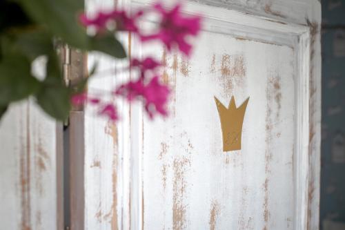 una puerta con una corona de oro con flores rosas en La Princesa y El Guisante, en Conil de la Frontera