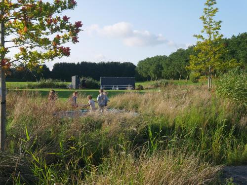 three children walking through a field of tall grass at Vakantiewoning Trimaarzate in Zwevegem