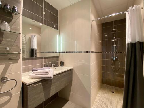 a bathroom with a shower and a sink and a mirror at Bethune City Relax Spa & Sauna in Béthune