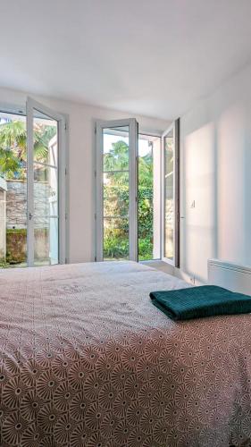 a bedroom with a large bed with sliding glass doors at L'Elégant - Idéal Couple - Parking Gratuit in Pau