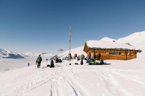 a group of people standing in the snow near a cabin at Hôtel Dents de Veisivi in Haudères