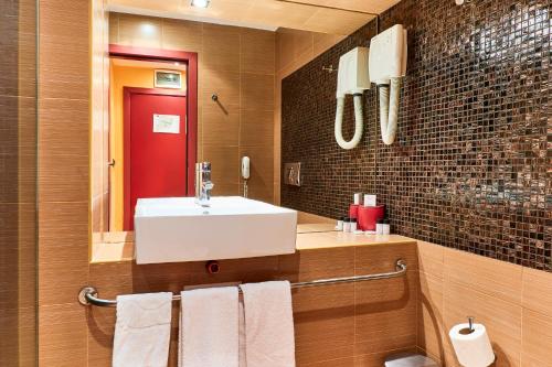 a bathroom with a white sink and a red door at Monet Hotel in Plovdiv