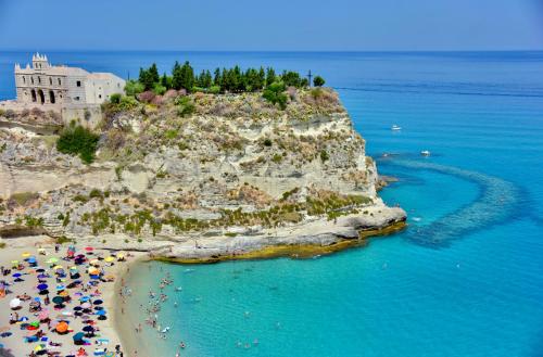 ein Strand mit Sonnenschirmen und Menschen im Wasser in der Unterkunft Le Twins -Bed and Breakfast in Tropea