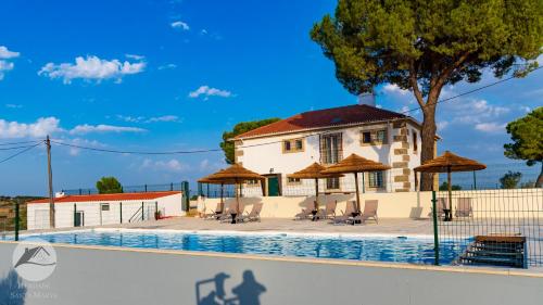 a building with a swimming pool with umbrellas at Alojamento Local Santa Marta in Zebreira