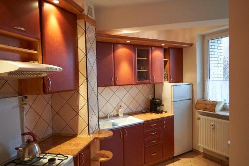 a kitchen with brown cabinets and a white refrigerator at Apartament Sybiraków in Białystok