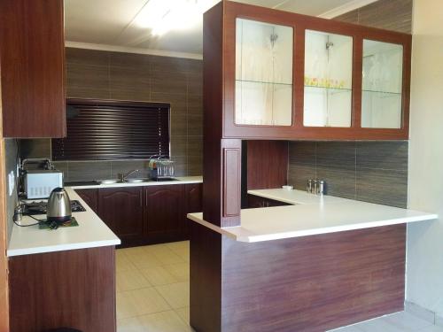 a kitchen with wooden cabinets and white counter tops at Parys In town Guest lodge and Conference Center in Parys