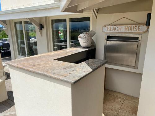 an outdoor kitchen with a beach house sign on the counter at Lasalle holiday home (Sun, Beach, Views, Fun for everyone!) in Plettenberg Bay