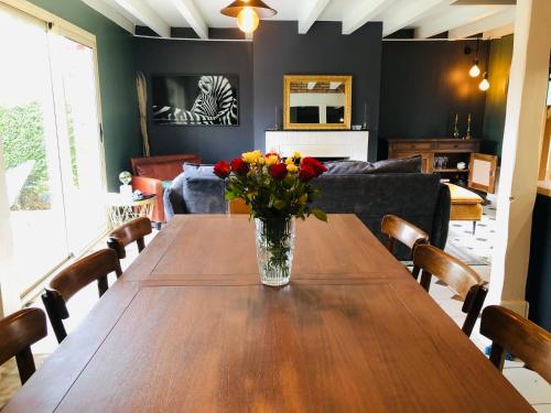une table en bois avec un vase de fleurs dessus dans l'établissement La maison, à Vittefleur