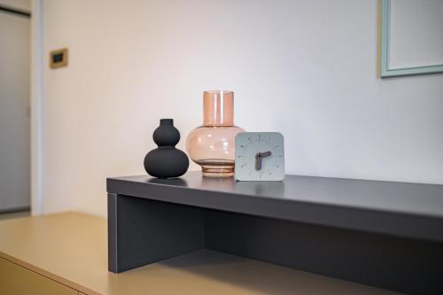 a table with two vases and a clock on it at Apartman EpiLux in Tuzla