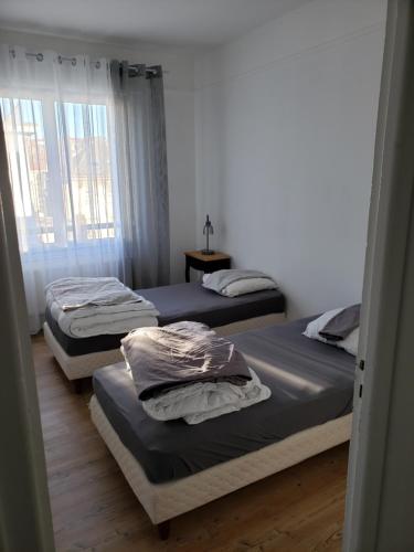 une chambre avec deux lits et une fenêtre dans l'établissement Bel appartement, à Boulogne-sur-Mer