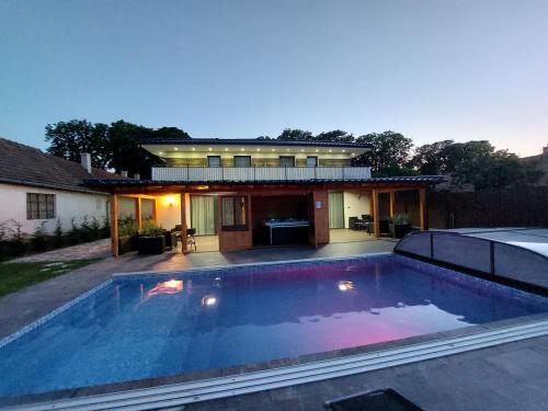 a swimming pool in front of a house at Sweet Home Apartman in Balatonszárszó