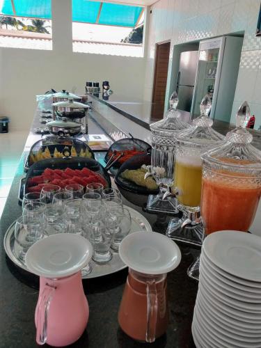 a buffet with glasses and plates and drinks on a counter at Paraiso Barra Hotel in Barra de Santo Antônio