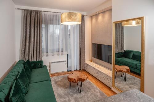 a living room with a green couch and a mirror at Apartman Istra- Titova vila in Zlatibor