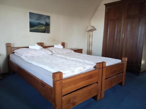 sypialnia z drewnianym łóżkiem z białą pościelą w obiekcie NA BANI-apartamenty i pokoje w Rabce