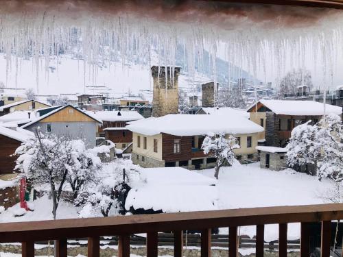 a town covered in snow with icicles hanging from a balcony at Hotel Svanseti in Mestia