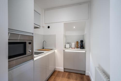 a kitchen with white cabinets and a microwave at Casa Fresa - Orchar Suites in Broughty Ferry