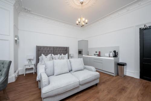 a living room with a white couch and a kitchen at Casa Fresa - Orchar Suites in Broughty Ferry