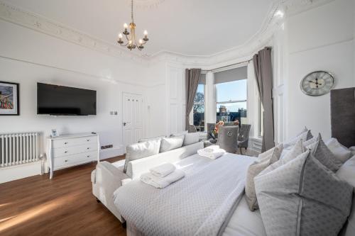 a white bedroom with a bed and a tv at Casa Fresa - Orchar Suites in Broughty Ferry
