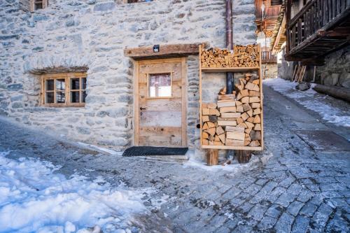 a pile of wood next to a building with a door at Rascard Monterosa in Champoluc