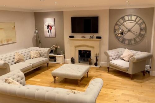 a living room with white couches and a fireplace at Stunning Oxfordshire 5 Bedroom House in 2 acres in Aston Rowant