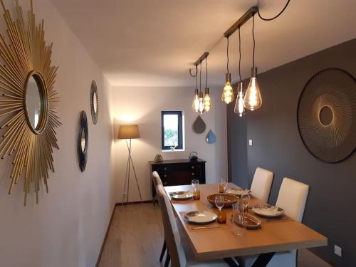 una sala da pranzo con tavolo, sedie e luci di Logement 80 m2 avec terrasses entre les deux abers a Landéda