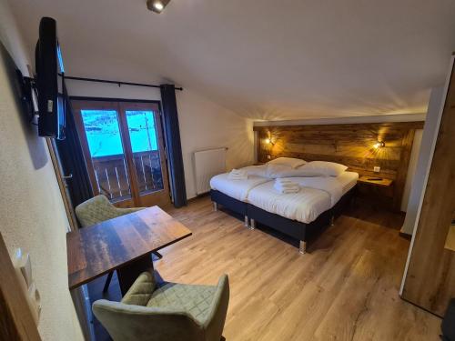 a bedroom with a bed and a table and a chair at Hotel Pension Annerlhof in Maria Alm am Steinernen Meer