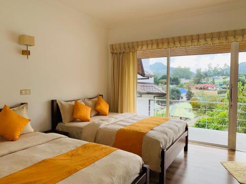 two beds in a room with a large window at Andora Nuwara Eliya in Nuwara Eliya