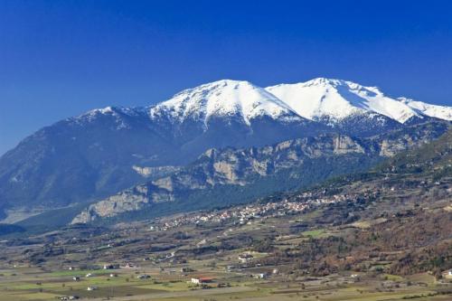 a snow covered mountain with a town in front of it at Angelic in the mountains in Kaisárion
