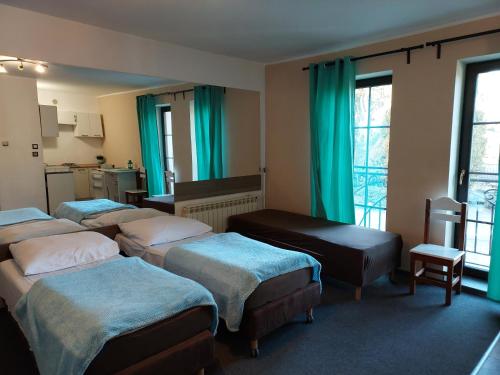 a hotel room with four beds and green curtains at Zajazd Jurajski in Podlesice