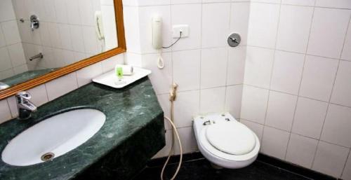 ein Badezimmer mit einem Waschbecken, einem WC und einem Spiegel in der Unterkunft Ramee Guestline Tirupati in Tirupati