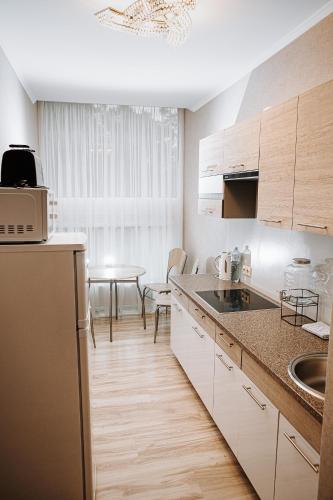 a kitchen with white cabinets and a table at Vallery Guest House in Bigauņciems