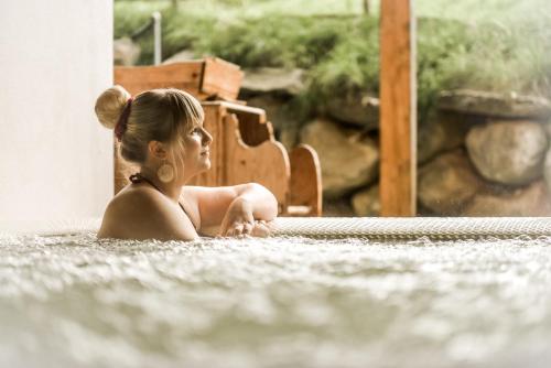 a young woman sitting in a hot tub at Hotel Amaten in Brunico