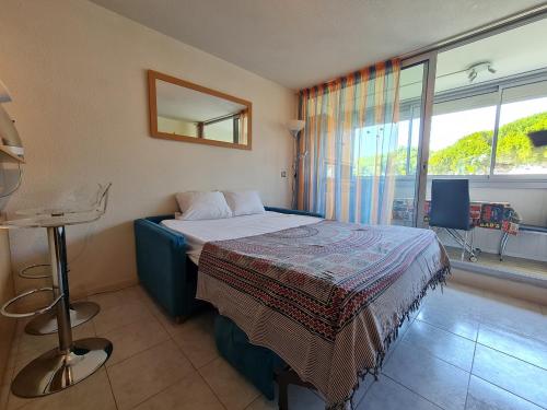 une chambre d'hôtel avec un lit et une fenêtre dans l'établissement Studio calme à 50m de la plage et petite vue mer, au Grau-du-Roi