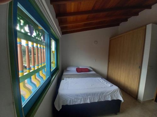 Habitación pequeña con cama y ventana en vista piedra, en Guatapé