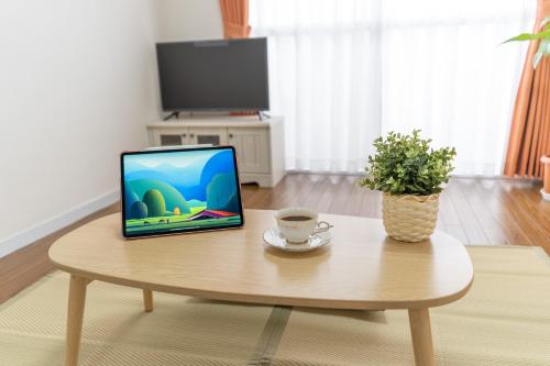 a laptop computer sitting on a table with a cup of coffee at stay's ジローズ浄心 602号 名古屋 民泊 駅近 in Nagoya