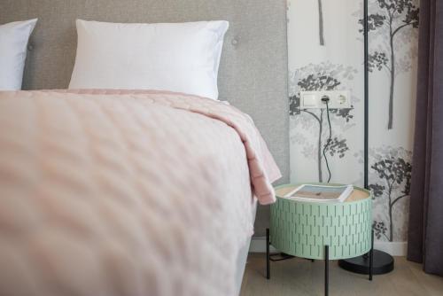 a bed with a pink blanket and a green night stand next to it at Apartment DoMiSol in Druskininkai